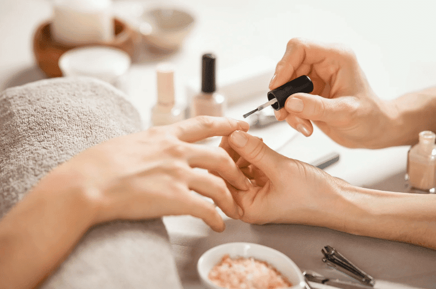 Woman receiving a manicure, nail polish being applied in a spa setting.