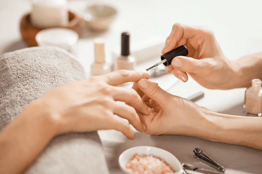 Woman receiving a manicure, nail polish being applied in a spa setting.