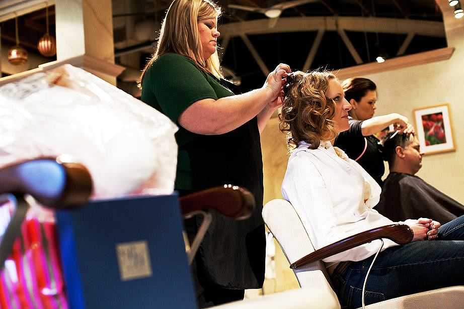Women styling customers' hair in a busy salon with elegant, modern décor.